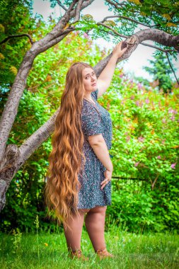 Plus size model posing against nature background. clipart
