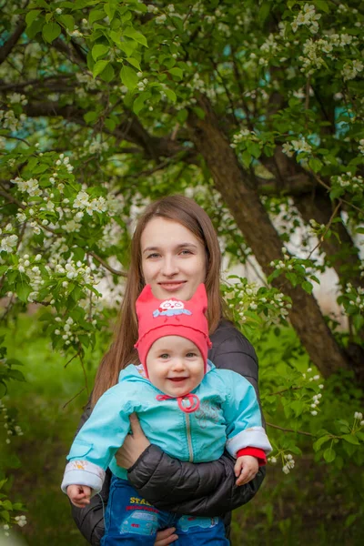 El concepto de maternidad. Madre e hija cerca de una cereza de primavera . — Foto de Stock