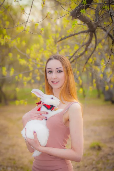 Portret van een mooi meisje met een konijn in haar handen. — Stockfoto