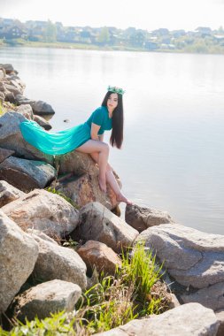 Yeşil elbiseli, trenli ve zümrüt renkli bir kraliçe. Gölde seksi bir esmer. Taşların üstünde kurbağalı bir kız. Peri doğası