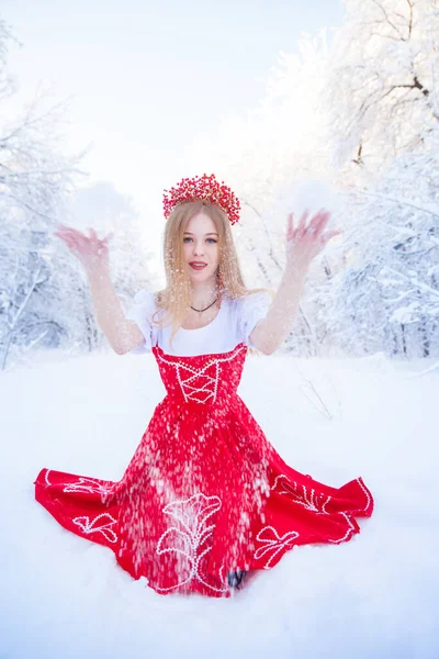 在冬天的森林里戴着一顶红色王冠的女王 可爱的女孩穿着俄罗斯红色的民族服装 迷人的金发美女 — 图库照片#