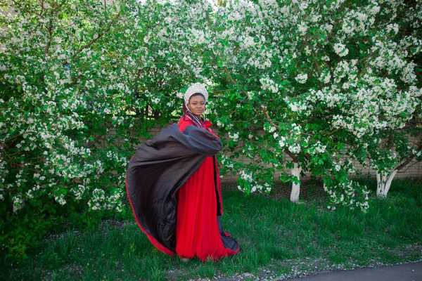 王冠と王室のマントルの女王 満開の庭を背景に素敵な女の子 赤でアフリカ系アメリカ人 — ストック写真