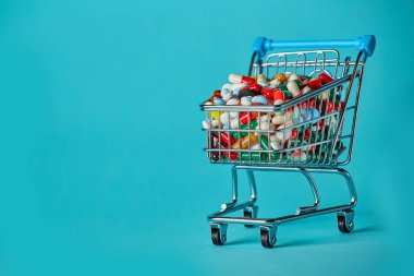 İlaç dolu bir alışveriş arabası. Mavi arka plan. Konsept: Dükkandaki tüm ilaçlar. Metin için alanı kopyala