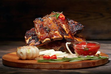 Kızarmış kaburga biberiye, soğan, sos ile ahşap bir yuvarlak tahta üzerinde. Koyu arka plan. Metin, boşaltmak için yer