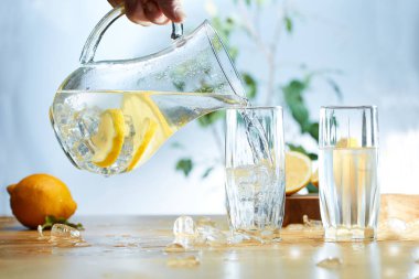 Su dilimlenmiş limon ile bir sürahi buz cam içine döktü.