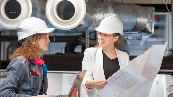 Girl tech and girl engineer look at thecheck the equipment. Team engineers discussing work together in site project. Concept of quality control and safety