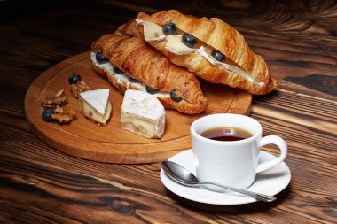 Kahve kruvasan, fındık, koyu ahşap arka plan Camembert peyniri ile.
