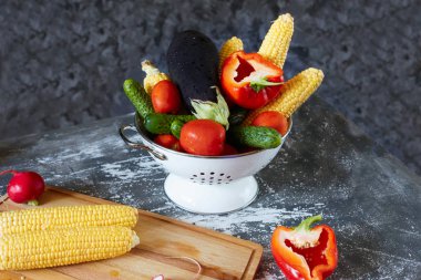 Karanlık bir arka plan üzerinde beyaz bir kase taze bütün sebze (Mısır Mısır koçanı, salatalık, domates, patlıcan ve biber).