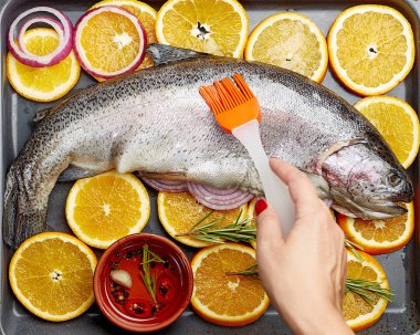 Taze somon fırın tepsisine portakal ile yalan. El Şef bir fırça ile som balığı yağı smear. Somon pişirme kavramı.