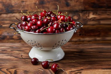 Olgun taze koyu ahşap arka plan üzerinde beyaz kase kırmızı kiraz yıkanmış