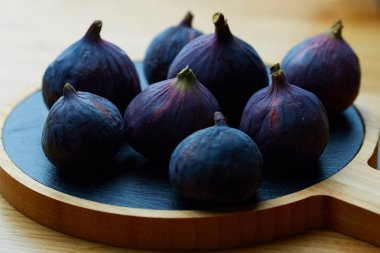 Ahşap arka plan üzerinde olgunlaşmış incir ile çanak.