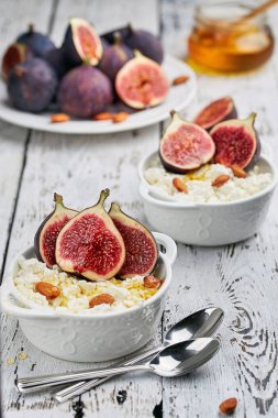 İncir, bal ve badem hafif bir arka plan üzerinde beyaz bir kase süzme peynir. Konsept: sağlıklı kahvaltı