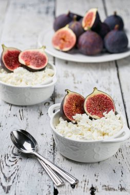 İncir ve badem hafif bir arka plan üzerinde beyaz bir kase süzme peynir. Konsept: sağlıklı kahvaltı