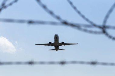 Dikenli tel arka plan üzerinde uçak uçar