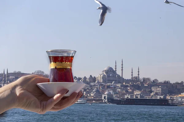 Hand holds a Cup of Turkish tea on a background of Blue mosque, Istanbul. Concept: Welcome to Istanbul, Turkey