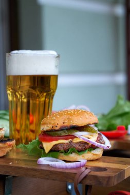Lezzetli büyük hamburger ve bira bardağı ahşap masada