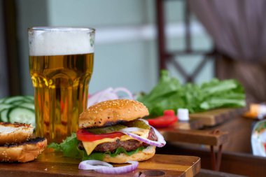 Lezzetli büyük hamburger ve bira bardağı ahşap masada