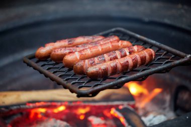 Mangal üzerinde orman akşam yemeği turist. Lezzetli sosisler ormanda akşam ateşinde kızartılır. ormanda et akşam yemeği Traveler ölen köz