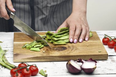 Şef kadın ahşap tahta üzerinde yeşil fasulye kesme