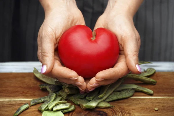 Tomato in the shape of a heart in female hands. Healthy food. — Stock Photo, Image