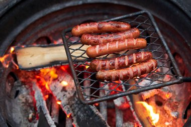 Mangal üzerinde orman akşam yemeği turist. Lezzetli sosisler ormanda akşam ateşinde kızartılır. ormanda et akşam yemeği Traveler ölen köz
