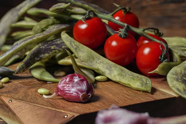 Greenbeans and cherry tomatoes in a wooden board on a rustic table. — Stock Photo, Image