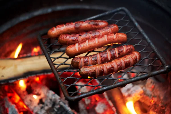 Forest Dinner tourist on grill. Delicious sausages are fried on fire in evening in the forest. dying embers of meat dinner traveler in forest — Stock Photo, Image