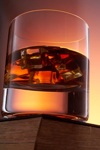 Pohár whiskyt jéggel egy régi könyvben. alsó nézetben. közelíti — Stock Fotó