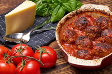 Domates tabağı köfte. rustik tablo. seramik kase. beyaz kafesli siyah peçete. sert peynir, taze basel, sarımsak parçası. çatal bıçak takımı ile hizmet