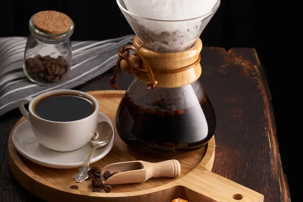 Pour over coffee brewing method. Making pour over coffee with hot water being poured from a kettle. a jug for pouring over coffee, a cup of coffee on a light wooden round tray, jam in a jar, coffee gr