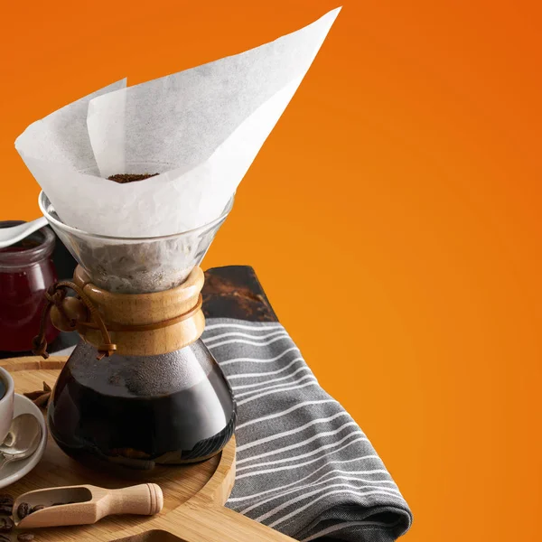 Pour over coffee brewing method. Making pour over coffee with hot water being poured from a kettle. a jug for pouring over coffee, a cup of coffee on a light wooden round tray, jam in a jar, coffee gr