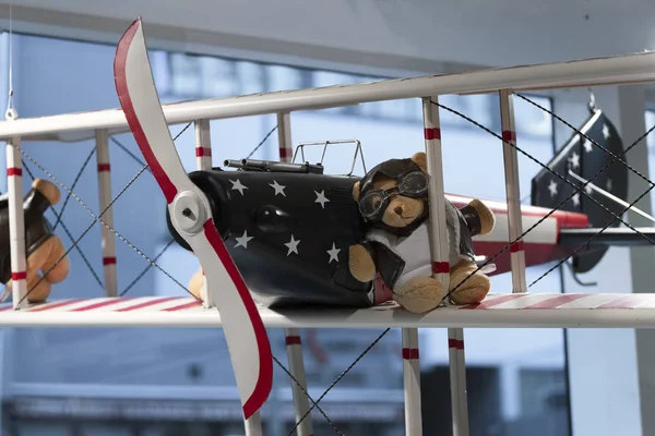 Teddybär in Pilotenbrille und Pilotenjacke auf dem Flügel eines alten Flugzeugs. Schaufenster. — Stockfoto