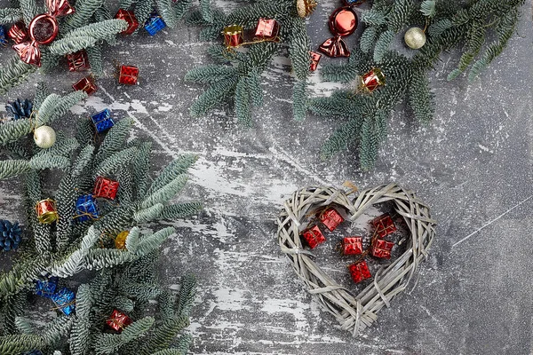 Christmas composition. on a gray background decorations in the form of a braided heart, gift boxes of red and blue flowers, fir branches with Christmas toys, flatlay — Stock Photo, Image