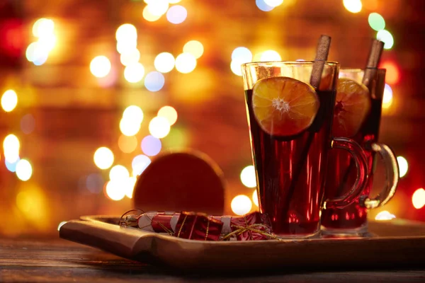 크리스마스 와인붉은 색은 와인에 계피 한 막대기와 반짝이는 빛을 배경으로 오렌지 한 조각 이담겨 있다. — 스톡 사진