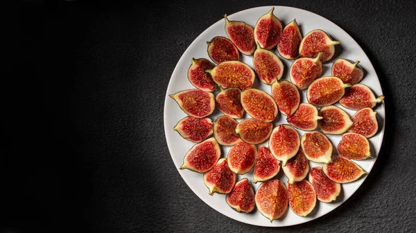 Figs cut into slices on a dark background. Space for text