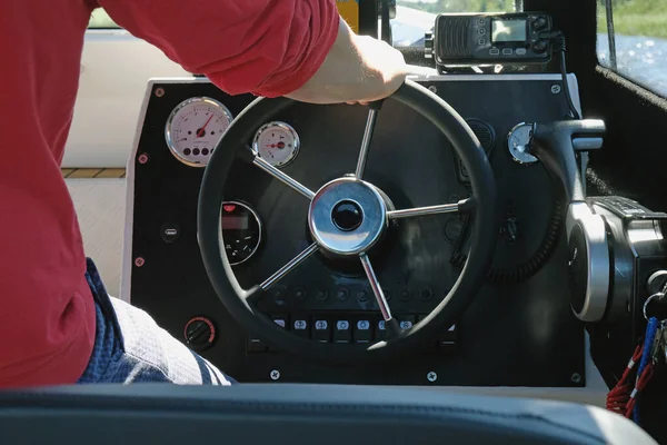 The captain at the wheel on the dashboard of the boat