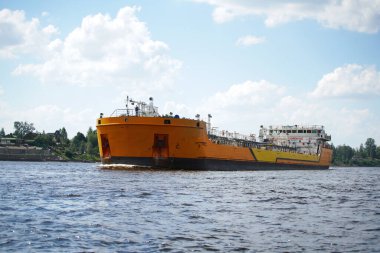 Nehir kargo gemisi bulutlu mavi gökyüzünün arka planında nehir boyunca ilerliyor.