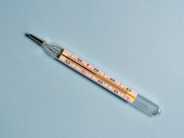 Mercury thermometer on a blue background, top view. Tool for changing the temperature of patients — Stock Photo, Image