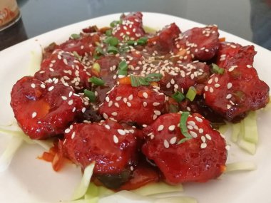 Kızarmış sulu tavuk parçaları bal, soya sosu, baharat ile marine edilmiş, beyaz bir tabakta susam tohumları serpiştirilmiş. Asya tarifi, Çin mutfağı.