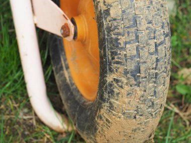 Bir inşaat el arabasının kirli tekerleğinin parçası. Yakın plan..