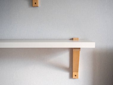 Odanın duvarında modern beyaz ahşap bir raf asılı. Modern iç tasarım