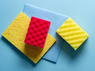 Değişik renk ve boyutlardaki temizlik süngerlerinin üst görünümü mavi bir arkaplanda serili