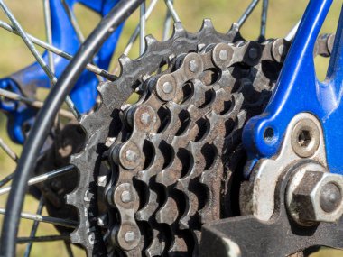 Dağ bisikletinin arka tekerleğindeki bisiklet vites mekanizması ve zinciri. Kirli arka kaset. Yıldızlar yağ ve toz içinde bisikletin üstünde.