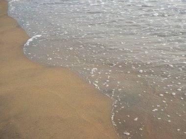 Yaz tatili boyunca kumlu bir sahilde deniz gelgiti.