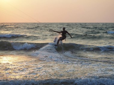 Hindistan, Goa, Arambol, gün batımında kıyıda uçurtma uçuran bir adam.