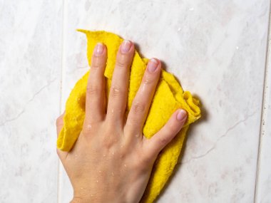 Banyodaki fayansları sarı bir bez ve temizlik ürünleriyle yıka. Evde hijyen sağlama kavramı