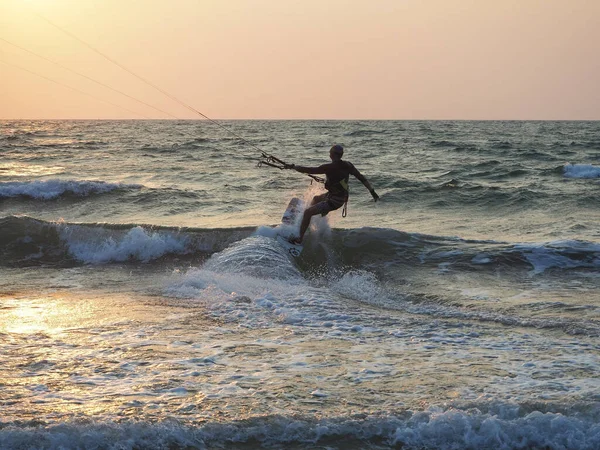 Hindistan, Goa, Arambol, gün batımında kıyıda uçurtma uçuran bir adam.