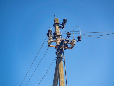 Mavi gökyüzü arka planında kabloları olan elektrik direği