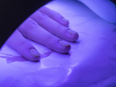 Kadın eli ultraviyole pençe altında. Verniği tamir etme süreci. Tırnak cilası.