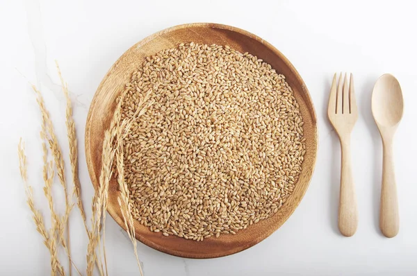 Wheat grains in the plate. top view Wooden Spoon and fork with a